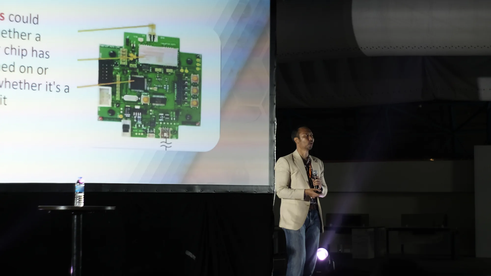 A speaker presenting a circuit board at StartIoT in 2017